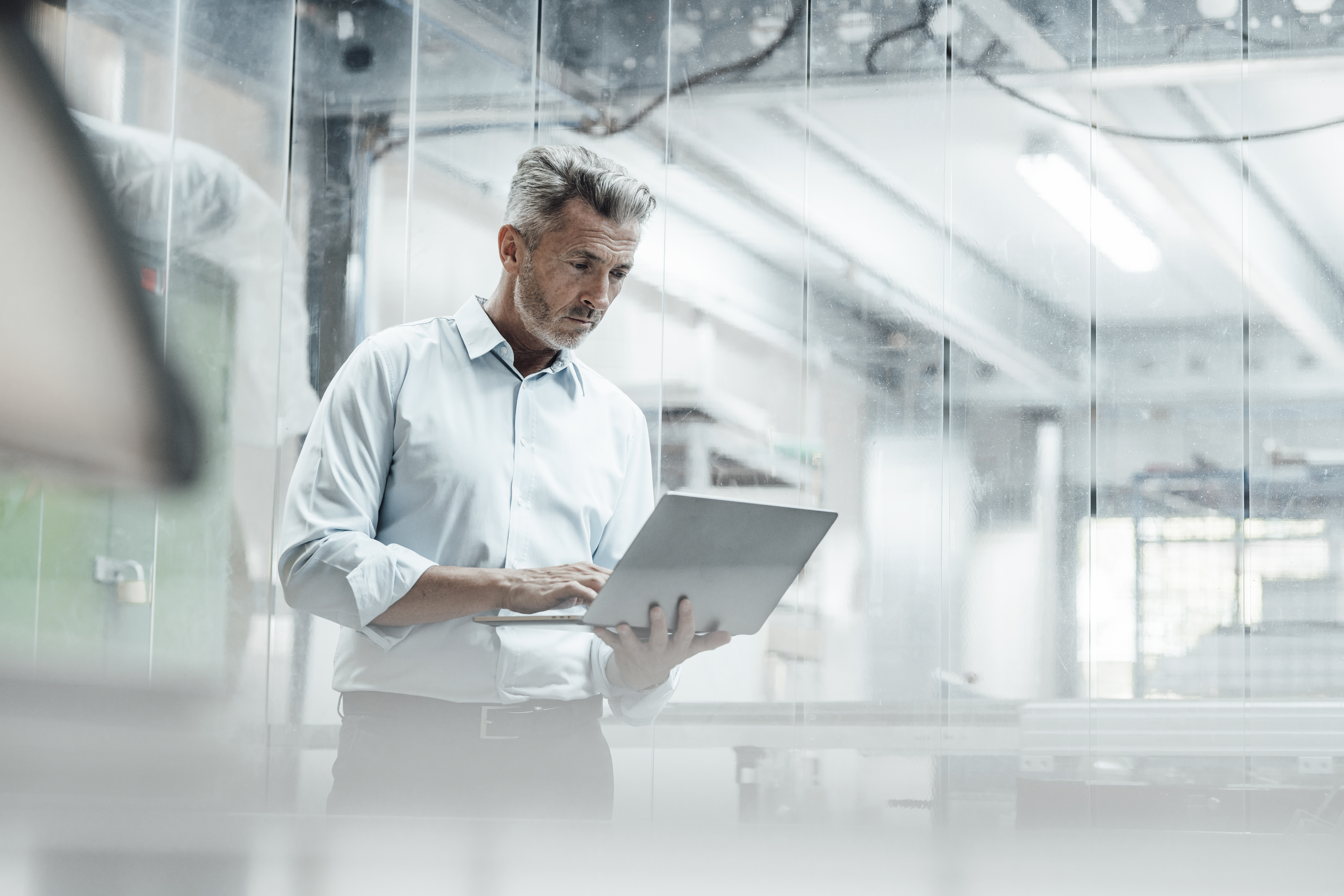 Thoughtful male engineer using laptop while standing in industry
